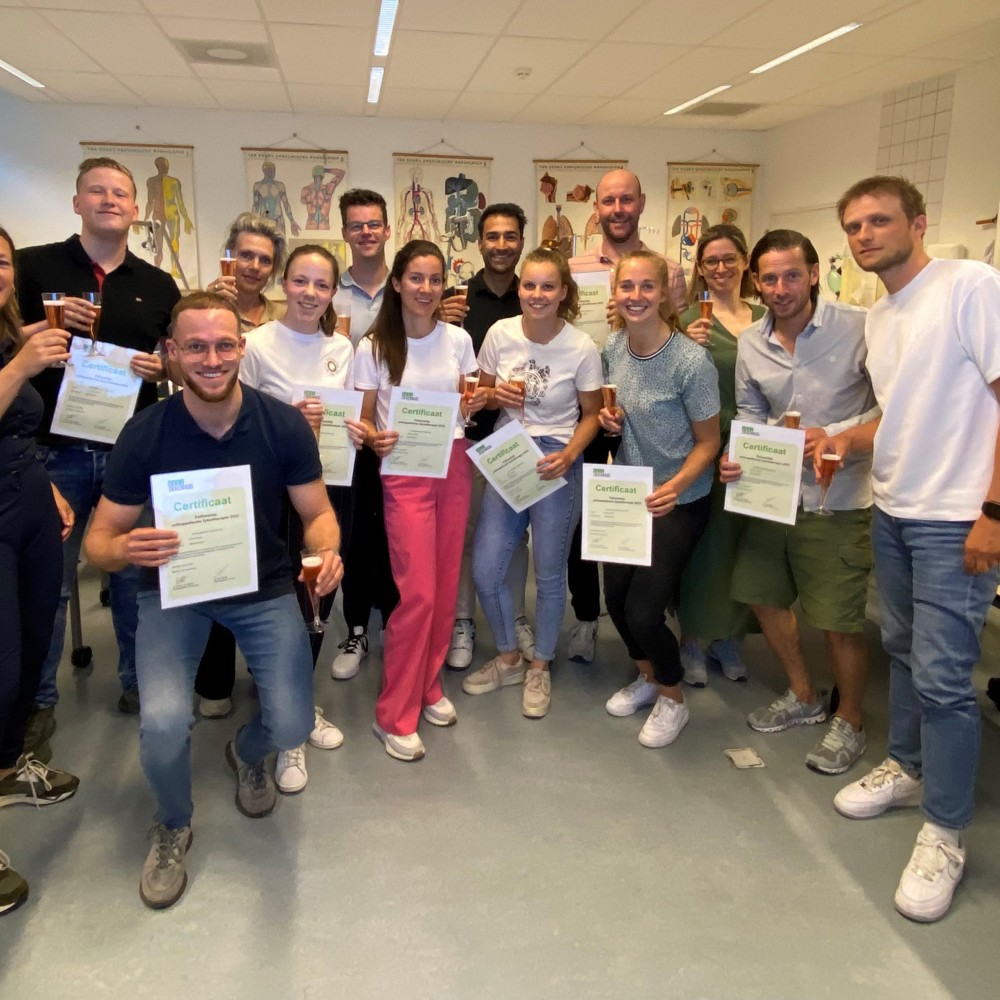 14 deelnemers op een rij proosten op afronden fellowship en houden certificaat vast